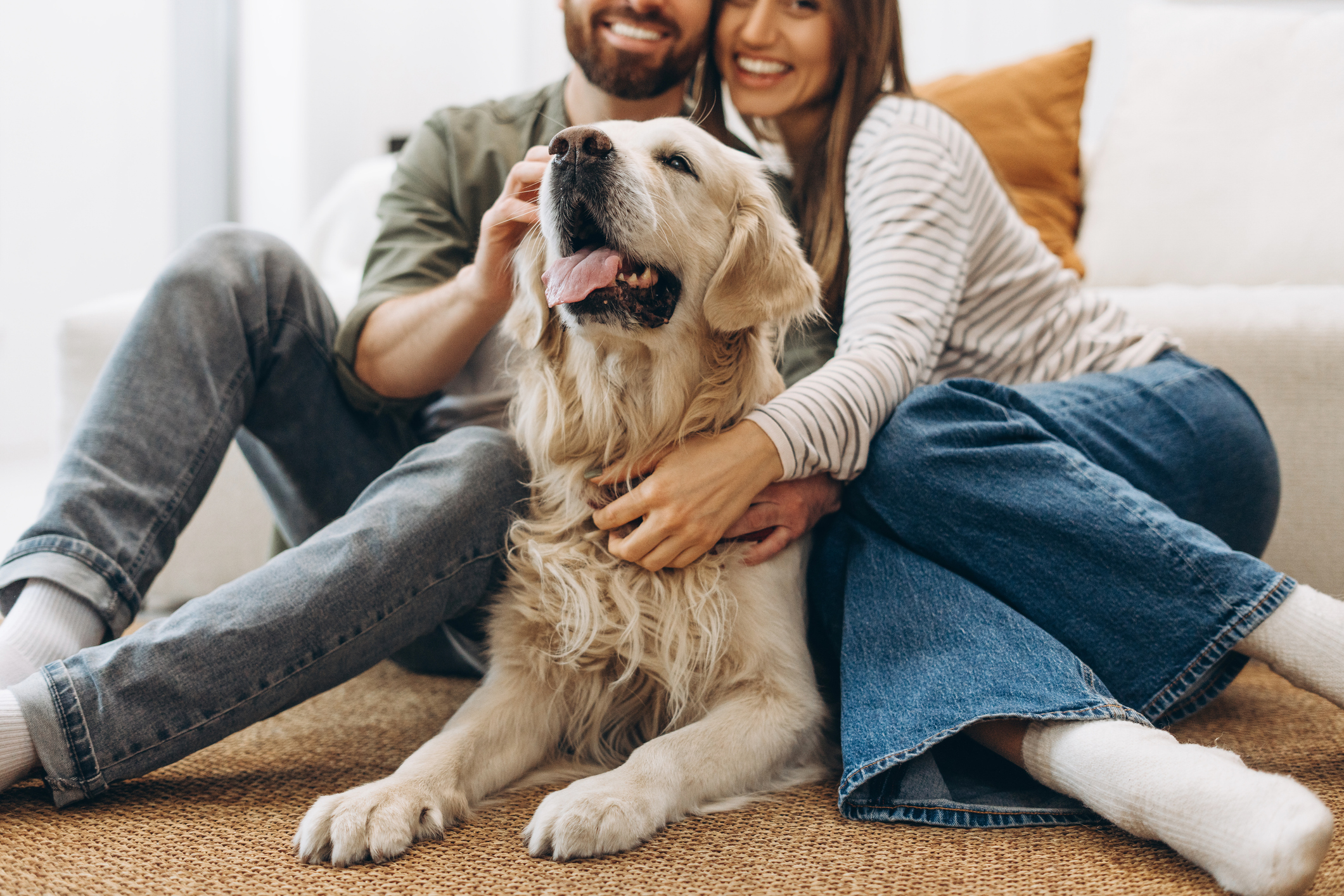 http://Smiling%20couple%20cuddling%20their%20adorable%20golden%20retriever%20dog%20in%20Bend,%20Oregon%20while%20relaxing%20on%20the%20floor%20at%20home,%20enjoying%20a%20cozy%20weekend%20in%20their%20home.